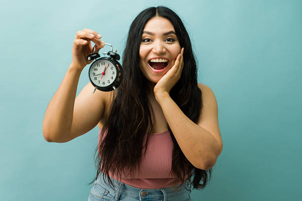 istock Excited woman holding alarm clock feeling surprised by time 2243968761