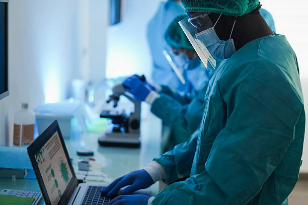istock Medical workers in hazmat suit working with microscope inside laboratory hospital wearing safety masks - Healthcare, longevity and medical research concept - Focus on african man face 2243969054