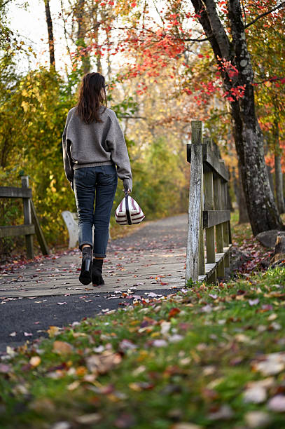 istock Woman walking on autumn park path enjoying solitude 2243969469
