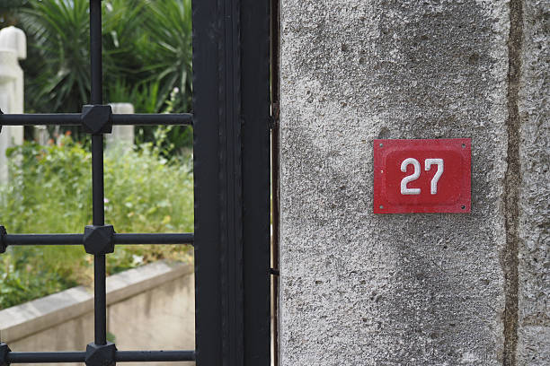 istock House number 27 displayed on a stone wall in a garden 2243971592