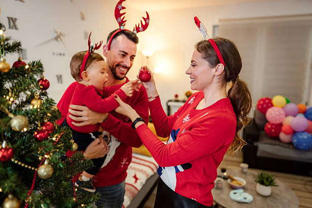 istock Family wearing festive sweaters decorating Christmas tree 2243973347