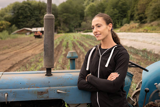 istock Confident young female farmer standing by tractor in field 2243975712