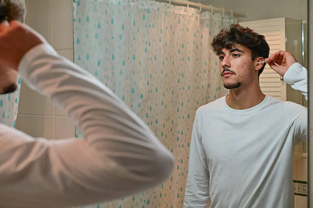 istock man cleaning ear with cotton swab at bathroom 2243976024