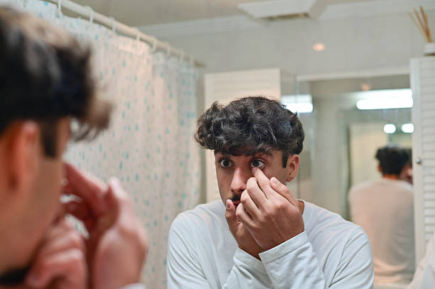 istock Man putting on contact lenses 2243976191