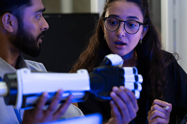 istock Engineer demonstrating advanced robotic prosthetic arm technology with colleague in research lab. Concept of innovation, artificial intelligence, robotics, human-machine collaboration, and future healthcare. 2243977063