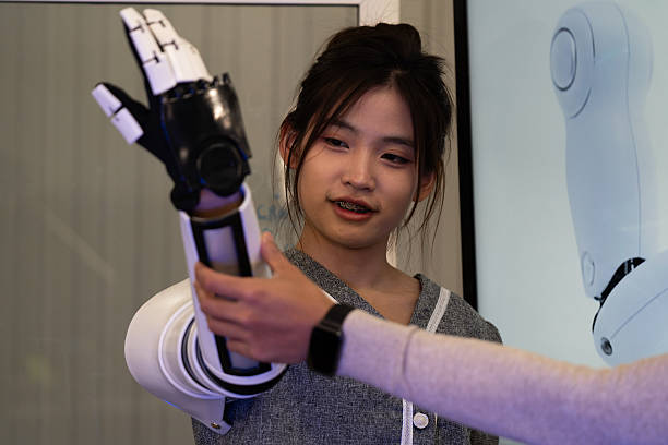 istock Engineer demonstrating advanced robotic prosthetic arm technology with colleague in research lab. Concept of innovation, artificial intelligence, robotics, human-machine collaboration, and future healthcare. 2243977077