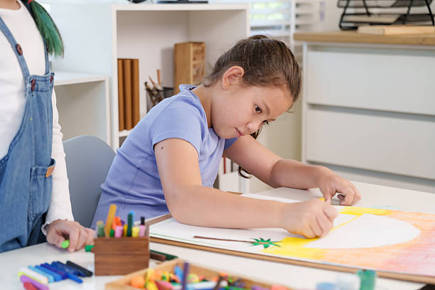 istock Caucasian elementary girl student drawing colorful artwork with crayons at classroom desk concentrating on details representing creativity imagination dedication childhood artistic learning process 2243979763