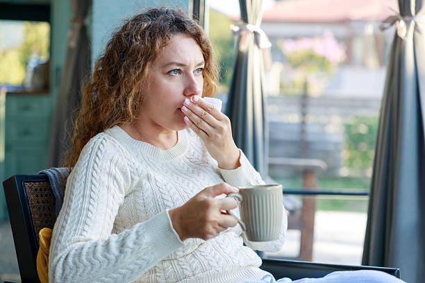 istock Young woman sitting on sofa and having cough 2243985854