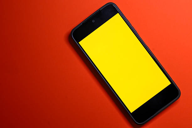 A modern smartphone with a clean bright yellow screen, placed diagonally on a rich orange (brick red) background. This provides a perfect canvas for adding custom content, text, or design, symbolizing technology, connection, and mobile marketing.