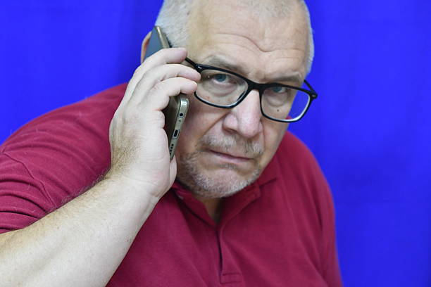 A male fashion model wearing glasses is talking on a cell phone