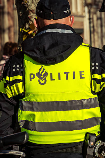 Dordrecht, Netherlands  November 17, 2018. A Dutch police officer on duty, seen from behind in uniform with a visible logo, representing law enforcement, authority, and public safety.