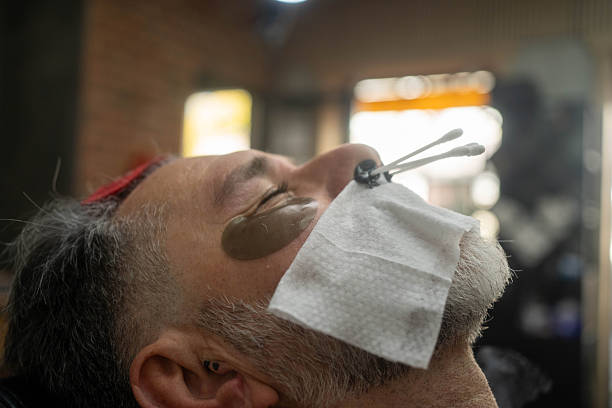 Master barber doing depilation beauty procedure in barbershop