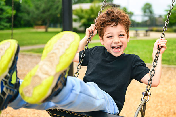 istock Happy 5 years old boy on a swing. Happy kid on playground 2243996955