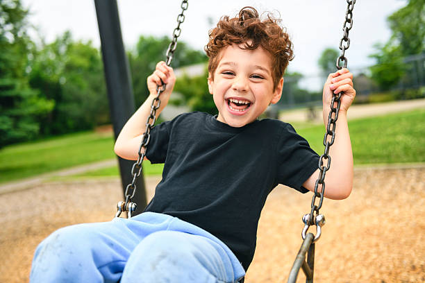 A Happy 5 years old boy on a swing. Happy kid on playground