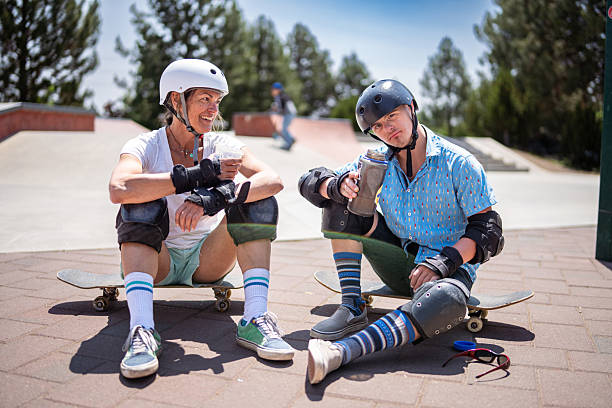 Young woman wearing roller skates lying on pavement, listening to music with headphones and using smartphone, outdoor leisure activity, lifestyle, relaxation, fun, digital technology,summer recreation