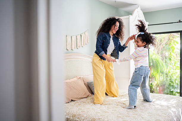 istock Mother and daughter dancing on bed at home 2243999833