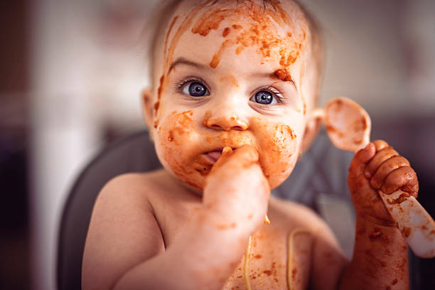 Little boy eating food with his mother in dining room