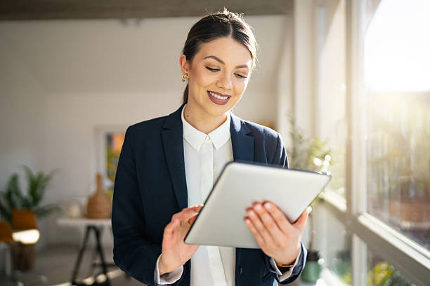 istock Young Smilling Business Woman Using Tablet in Modern Bright Office 2244000352