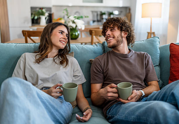 istock Young couple relaxing on couch smiling and talking 2244000626