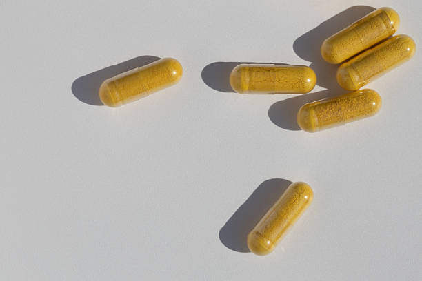 istock Yellow capsules on a light background. Medicines scattered on the table. 2244007906