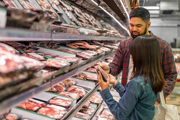 Authentic Asian American father and daughter grocery shopping,  using their cell phone making choices based on comparrasion shopping.