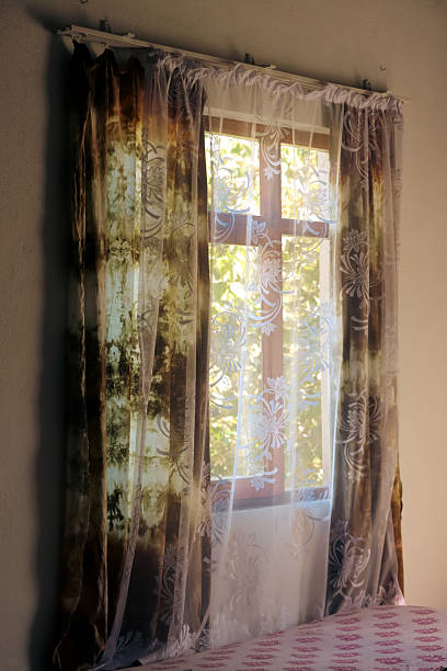 istock Old window with vintage curtains in soft sunlight 2244012048