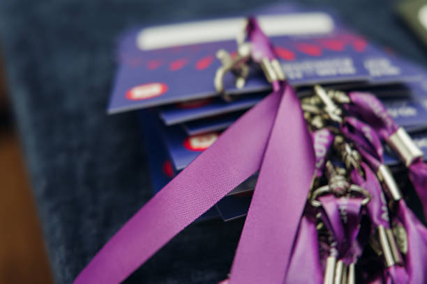Process of checking in on conference congress forum event, registration desk table, visitors attendees receiving violet lanyard with name purple badge, entry wristband bracelet and electronic ticket