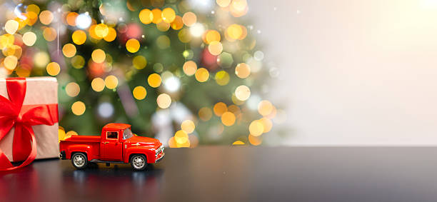 Christmas banner, red car, gift, Christmas tree with blurred lights. Holiday Background With Copy Space Blurred Lights And Highlights Gold Lights Christmas Gift With Red Ribbon