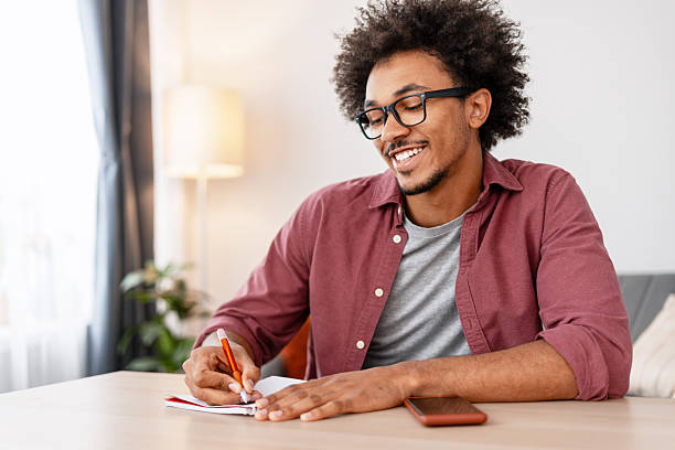 istock Authentic African American man writer taking notes sitting working at home in modern living room 2244024090