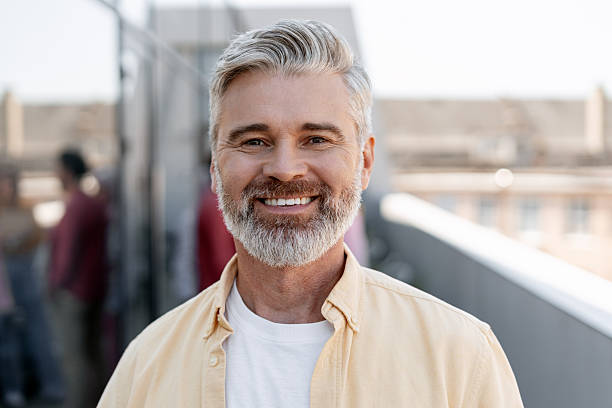 istock Successful bearded gray haired man wearing casual clothes looking at camera posing on the street 2244025890