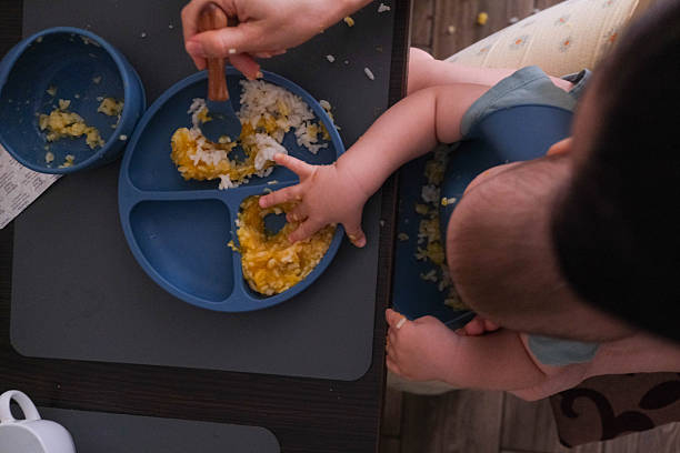 istock Baby Eating Rice and Eggs with Spoon 2244029737