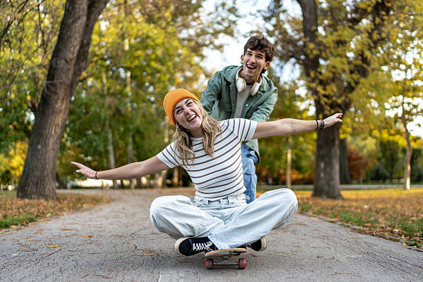 istock Young couple playing with skateboard in autumn park 2244030782