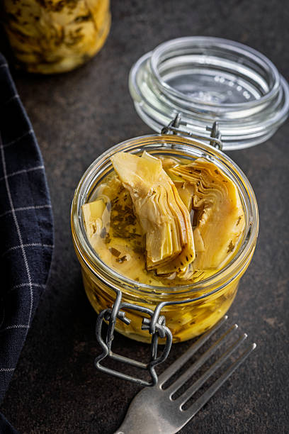 istock Pickled artichoke in jar on black table. 2244031059