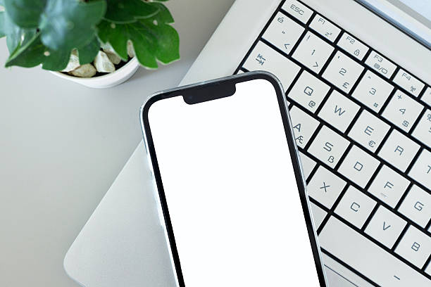 istock Smartphone with blank white screen on laptop over gray desk 2244039311