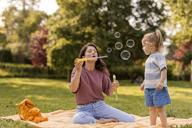 istock Happy Mother and Daughter Playing with Bubbles in Park 2244043736