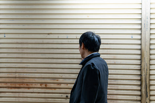 Businessman Inspecting an Aged Shutter、Checking the Condition of a Storefront Roller Shutter