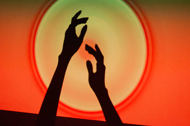 istock Hands reaching towards a glowing circle on a vibrant red and orange background during a creative event 2244047750