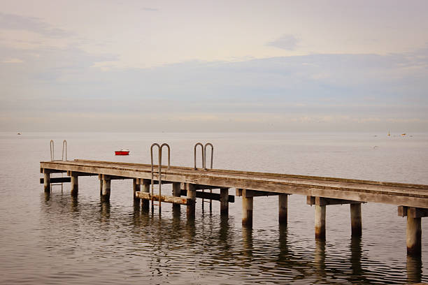 view of old pier over calm water at sunrise