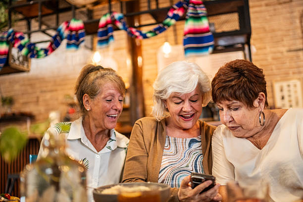 istock Senior friends women talking and using mobile phone at restaurant 2244049042
