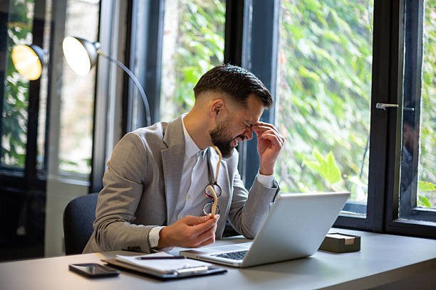 istock Stressed businessman having strong headache working on laptop 2244050351
