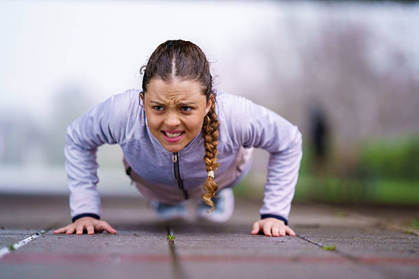 Young woman working out outdoors, pushing herself during fitness training.