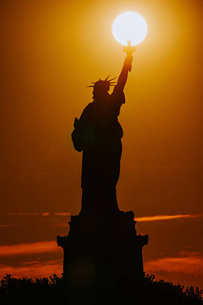 At sunset, Liberty Island transforms into a tranquil haven bathed in the warm hues of the fading day. The Statue of Liberty stands as a silhouette against the colorful sky, embodying a sense of serenity and freedom amid the breathtaking twilight.