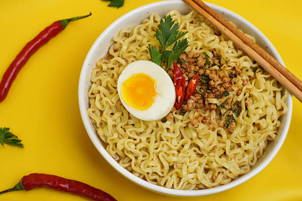 istock Instant Noodles with Boiled Egg and Chili Garnish on Yellow Background 2244058084