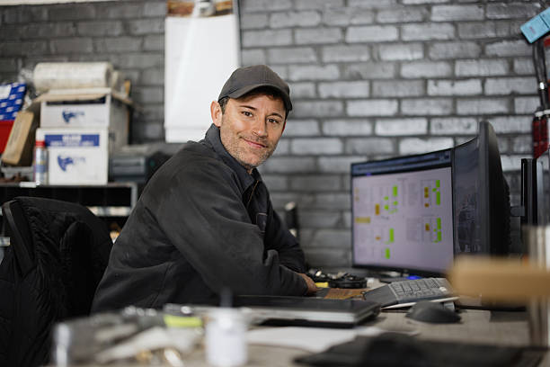 istock Mechanic working on computer in auto repair shop smiling at camera 2244059210