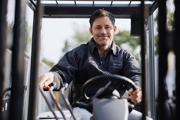 Portrait of a smiling warehouse worker driving a forklift truck in a warehouse or storage facility