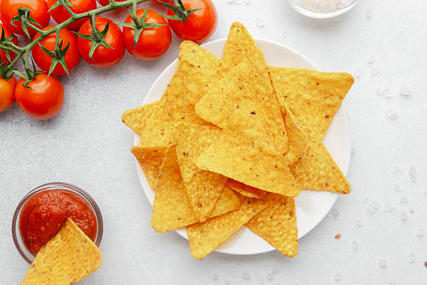 istock Crispy nacho chip in salsa bowl with plate of chips and fresh tomatoes 2244059836