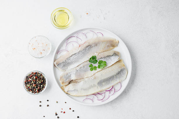 istock Marinated herring fillets with red onion, spices and herbs on white plate 2244059989