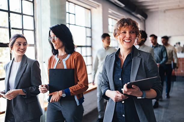 istock Professional Group Walk Through Modern Office Hallway With Smiling Colleagues Carrying Tablets 2244066195