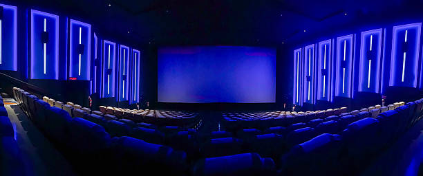 istock A pristine cinema hall with rows of plush, blue seats, a grand, illuminated screen, and subtle ambient lighting, creating an inviting atmosphere ready for the next audience. 2244070314
