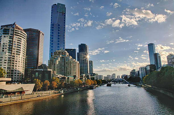 A picturesque view of Melbourne's cityscape featuring the Yarra River and modern skyscrapers under a clear blue sky.